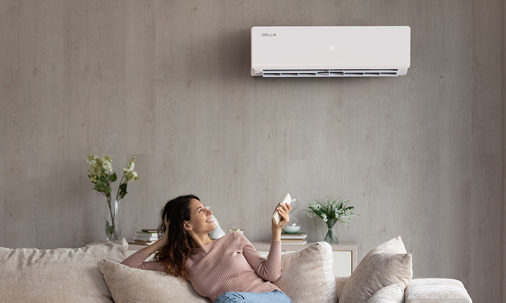 A woman is sitting on the sofa controlling the air conditioner