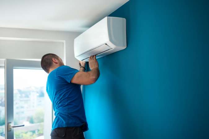 A man is installing a mini split AC: Cost to Install Mini Split AC System